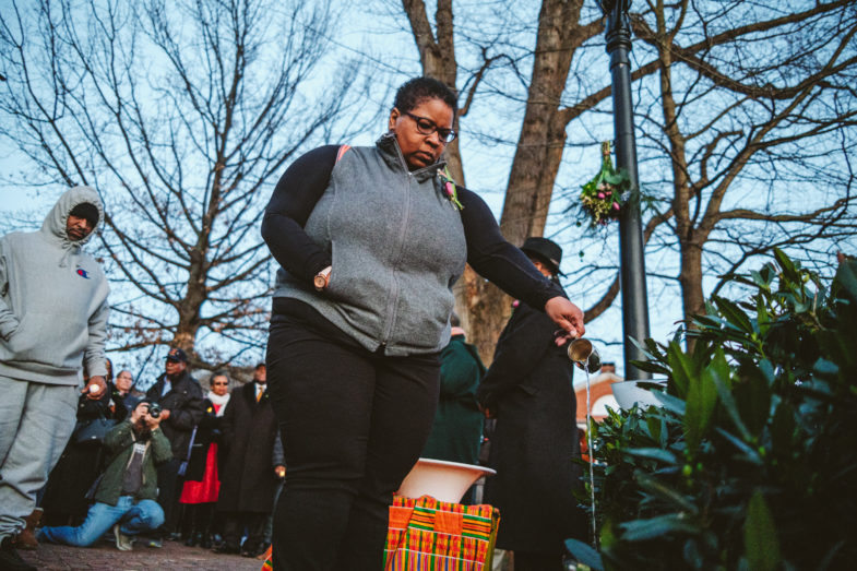 Myra Anderson, a sixth-generation descendant of the Hern family, who were enslaved at Monticello, pours a libation on March 1, 2020 at the Albemarle County Courthouse as part of a slave auction vigil. Photo: Ézé Amos 